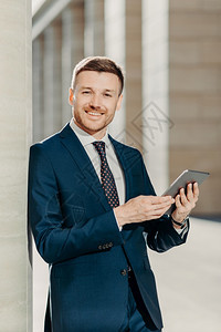 英俊的男经济学家在数字平板电脑上在线搜索信息准备与工作人员会面编写财务报告穿成正规服装图片