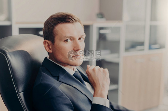 正式诉讼专业男经理直接看镜头坐在工作场所的椅子上为新商业项目打拼优雅的男经理在自己公司或工作图片