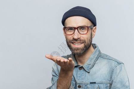 穿着时装的长胡子男欣喜地表达他的爱展示空气之吻现欢快的表情与灰色背景隔绝面带欢快的表情蓝眼中年男子穿着时装在室内做姿势图片