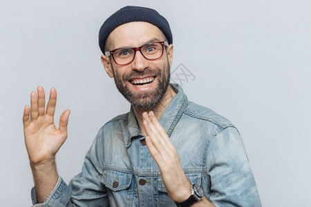 快乐的中年男人肖像在室内很快乐举手有的表情戴眼镜帽子和穿着衣服与白色背景隔绝人积极的情感和图片