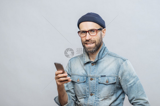 具有吸引力的中年男模范穿着时装拥有智能电话与同居网络中的事或朋友聊天与白人背景隔绝图片