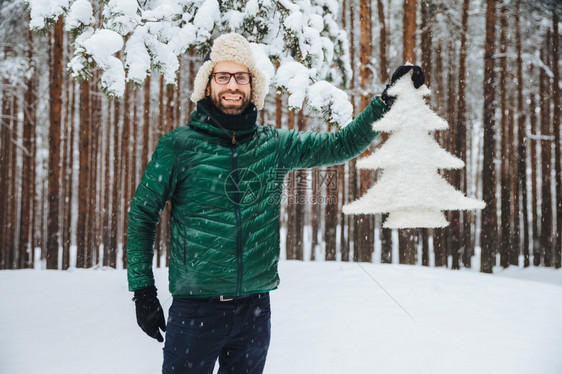 看这棵美丽的fir树快乐的长胡子着毛帽的男人带着耳翼和绿动脉很高兴在冬季森林中行走享受美丽的树木和自然景观季节概念图片