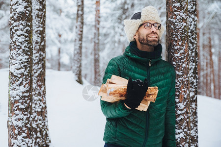 长着微笑的男在户外画像站树上沾着雪拿木柴图片