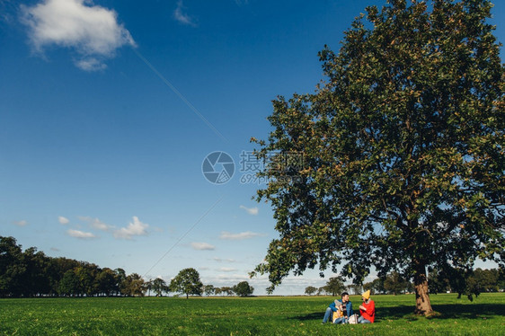 青蓝天空和绿草美丽的秋天和风景三人在草地上喝户外茶图片