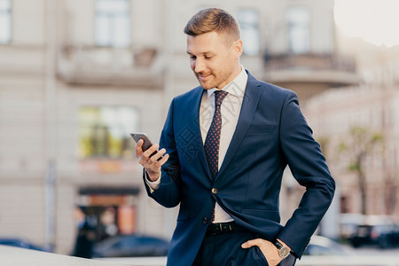 成功男创业者将现代智能手机掌握在中的照片读取来自金融交易浏览互联网在线付款工间休息去咖啡馆或餐的消息图片