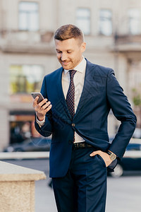 男经理穿着优雅的西装手持口袋使用智能电话总是保持联系在互网站上读商业新闻图片