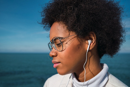 年轻拉丁女在背景音乐生活方式上聆听音乐耳机和海洋的音乐图片