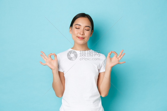 快乐的平静和耐心亚裔女肖像闭上眼睛微笑的喜悦握着手在莲花的姿势到达尼尔瓦纳静下来的默思蓝背景快乐的平静和耐心亚裔女肖像达到尼尔瓦图片