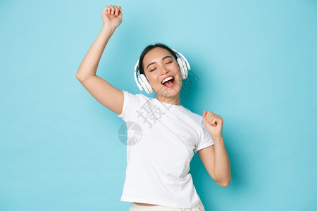 购物金钱和融概念欢快的亚洲女孩穿白色散装t恤唱卡拉ok播放音乐应用程序听无线耳机音乐并享受完美的声音购物播放音乐应用听无线耳机音图片