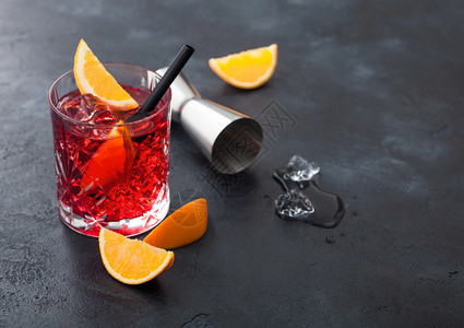 晶玻璃中的白葡萄鸡尾酒有橙色切片和新鲜生橙子黑色底有吉格和冰块图片
