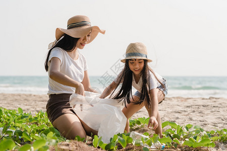 在海滩上收集塑料垃圾的年轻快乐家庭活动asi志愿者帮助保持自然清洁图片