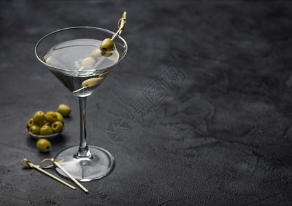 伏特加马提尼酒鸡尾原杯装橄榄在金属碗和竹棍黑色背景图片