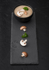 黑色的碗盘奶油栗子辣椒香菇汤黑色背景石板和新鲜蘑菇图片