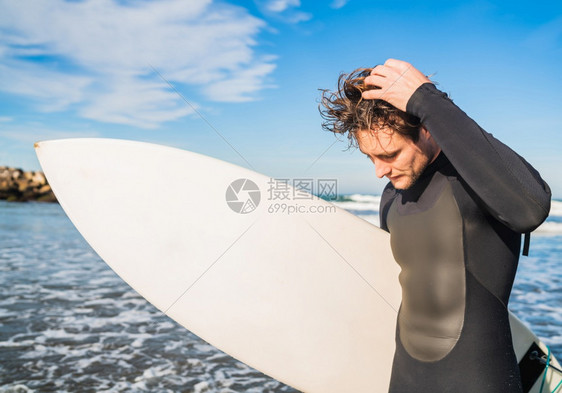 年青的冲浪者站在海洋中穿着黑色冲浪西装的板运动和水上的概念图片