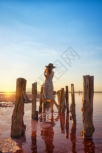 女孩在日落时著名的粉红盐湖上图片