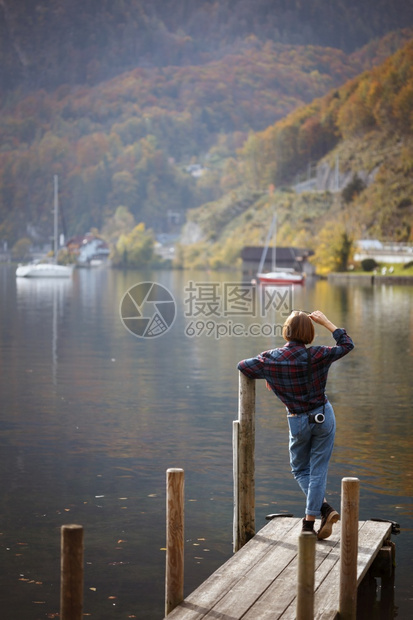 少女站在湖边的码头上和山的背景图片