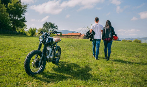 在野外行走的夫妇手牵停着摩托车图片