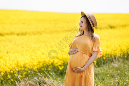 美丽的孕妇在公园戴草帽图片
