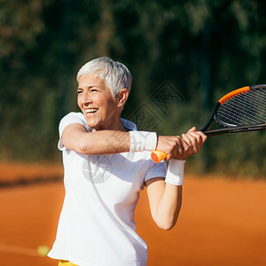 积极的成年妇女娱乐地打网球图片