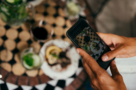 在素食餐厅用智能手机拍摄生蛋糕的妇女图片