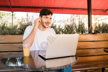年轻人坐在咖啡店时使用笔记本电脑的肖像图片