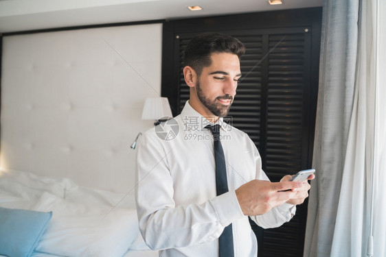 年轻商人在旅馆房间使用手机的肖像图片