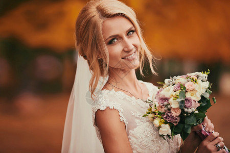 美丽的新娘在秋天公园闻到婚礼的花束当天关门图片