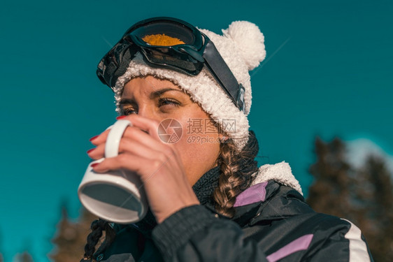 女人喝咖啡或茶享受山上冬日的图片