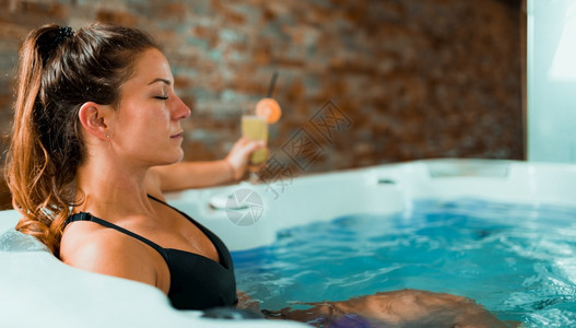 美丽的女人在温泉中心享受按摩浴缸喝柠檬水和放松美丽的女人在温泉中心享受按摩浴缸图片