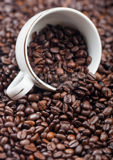 新鲜芳香烤咖啡豆背景中含有咖啡豆的白陶瓷杯图片