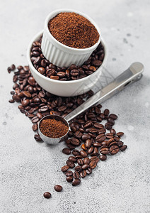 新鲜生有机咖啡豆以白碗和粉末制成以桌边背景和圆钢勺为原料图片