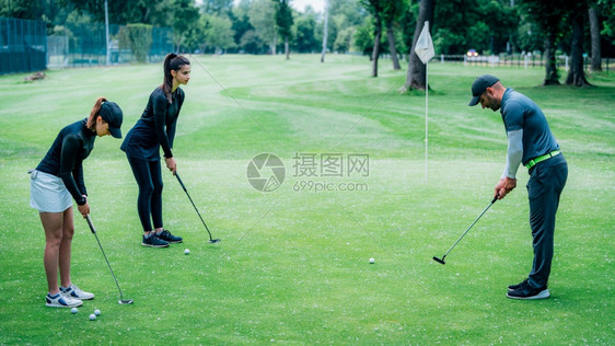 在高尔夫球场上与年轻妇女一起学习高尔夫教练图片