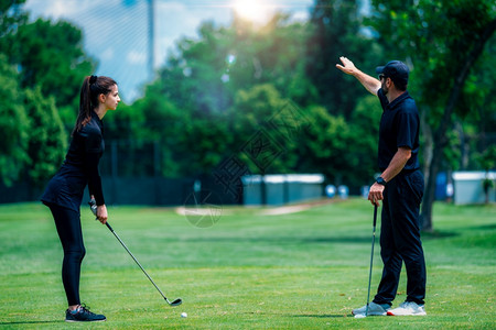 年轻妇女与高尔夫教练一起打高尔夫图片
