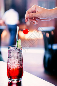 鲜冰的冷闪亮樱桃柠檬鸡尾酒餐桌上杯子清晰的冰块女人用手从鸡尾酒杯里摘樱桃图片