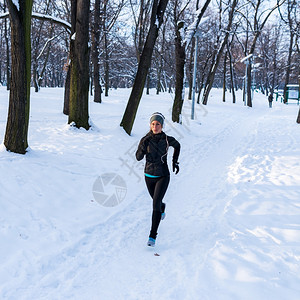女运动员冬季在公园听着音乐慢跑图片