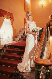 身着白色礼服双手拿着一束花朵的美丽年轻新娘肖像婚礼当天一位身着白色礼服双手拿着一束花朵的美丽年轻新娘肖像图片
