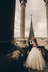 在古老哥特大教堂阳台上拥抱的新郎新娘图片