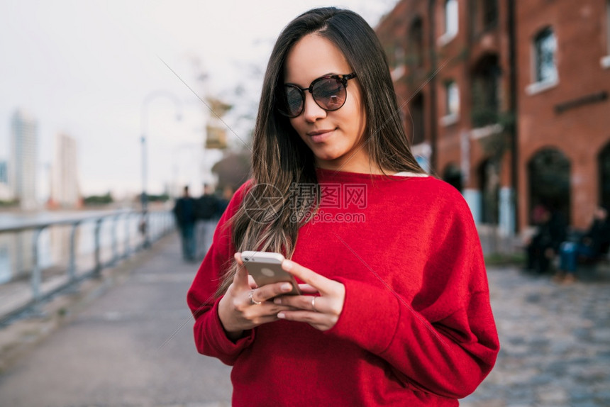 年轻美女在街上户外使用手机的肖像图片