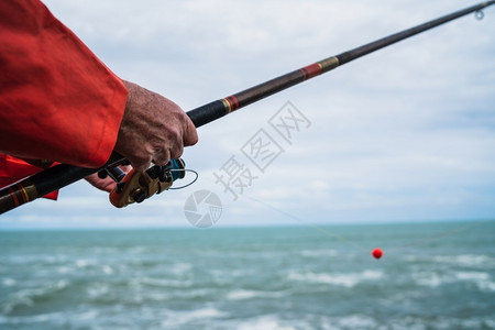 近距离接一个渔夫持有捕鱼杆和体育概念图片