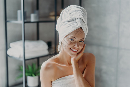 美貌的欧洲女有化妆品皮肤很少有健康的发光皮肤用浴巾包着在家里享受休息SPA女在浴室里摆姿势美貌健康的概念图片