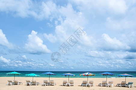 蓝色天空下的绿海白云和多彩的海滩雨伞在布吉的卡塔海滩图片