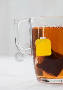 黄色标签黑茶叶袋白背景的清晰玻璃杯图片
