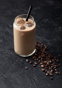 一杯冰冷的咖啡和牛奶黑桌底的鲜生咖啡豆图片
