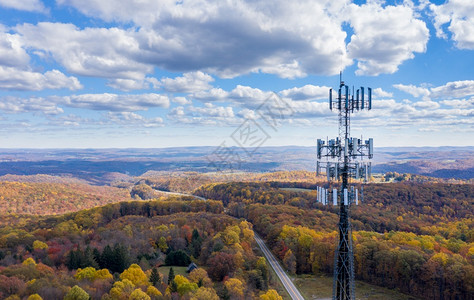 水彩天空位于西弗吉尼亚州森林农村地区上空的乌比亚电话手机塔的空中观察以说明缺乏宽带互联网服务提供宽带服务的西弗吉尼亚森林地区手机或移动服背景