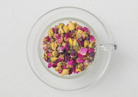玫瑰花芽在白色背景的清晰玻璃杯中混合茶叶顶部视图图片