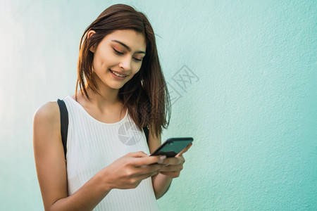 年轻拉丁裔女使用手机在街上户外拍摄肖像图片