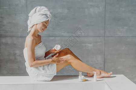 长着细腿的漂亮女人横向一 将润湿乳油加在健康的皮肤上 享受美丽的常规图片