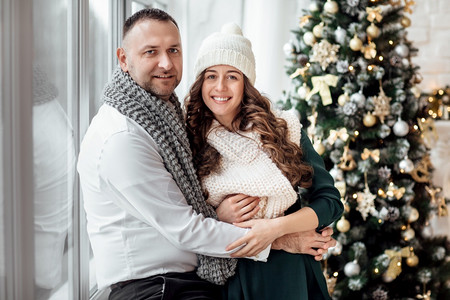 新年情人节爱浪漫的概念庆祝圣诞节年轻夫妇的假期衣服拥抱在圣诞树附近浪漫的概念背景图片
