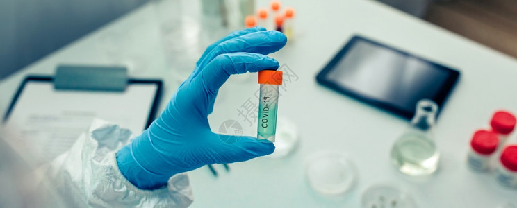 科学家用手在实验室中疫苗展示小瓶有选择地关注前方小瓶图片