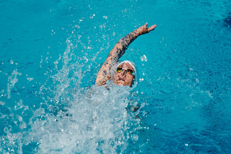 女有纹身在训练中游泳回击背景